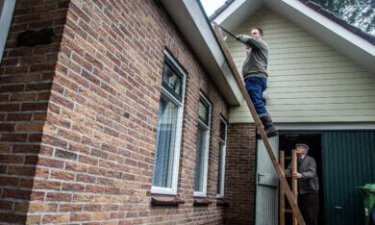 Vrijwilliger Rick Visscher van Vrijwilligersnetwerk Wagenborgen maakt de goot schoon van Dhr Kuiper